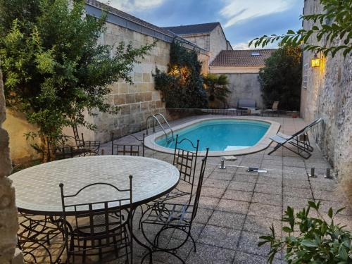 un patio avec une table et des chaises à côté d'une piscine dans l'établissement La maison margalaise, à Margaux