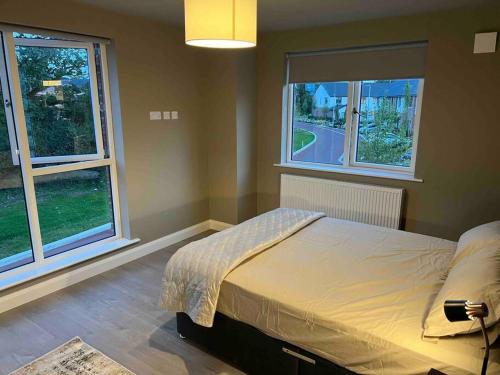 a bedroom with a large bed with two windows at 3 bed rooms Vip family house in Dublin