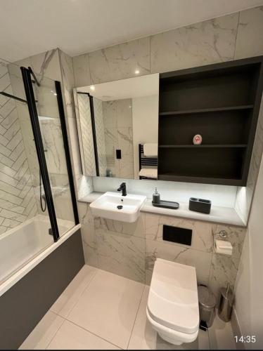 een badkamer met een wastafel, een toilet en een bad bij Zencityhomes in Barking