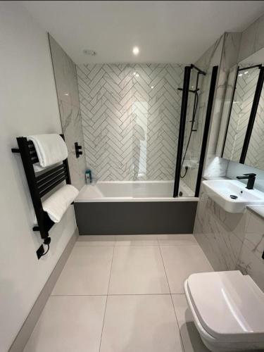a bathroom with a tub and a toilet and a sink at Zencityhomes in Barking