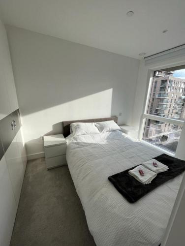a white bedroom with a bed and a window at Zencityhomes in Barking
