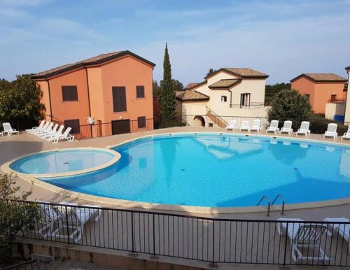 une grande piscine avec des chaises et un bâtiment dans l'établissement Les terrasses de Lozari, à Belgodère
