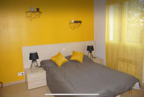 a bedroom with a bed with two yellow pillows at Les terrasses de Lozari in Belgodère