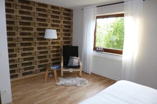 een slaapkamer met een stoel en een bakstenen muur bij Haus Weinheck in Lebach