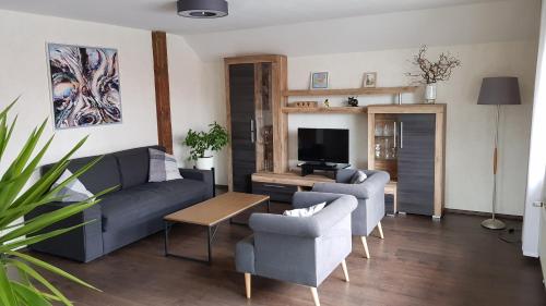 a living room with a couch and two chairs and a television at Haus Weinheck in Lebach