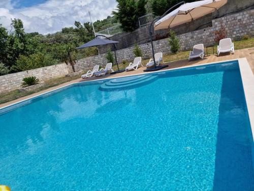 ein großer blauer Pool mit Stühlen und einem Sonnenschirm in der Unterkunft Villa Bella in Bar