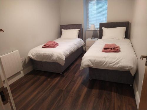two beds in a small room with wood floors at Spacious Two bedroom City apartment Longs Place, Dublin 8 in Dublin