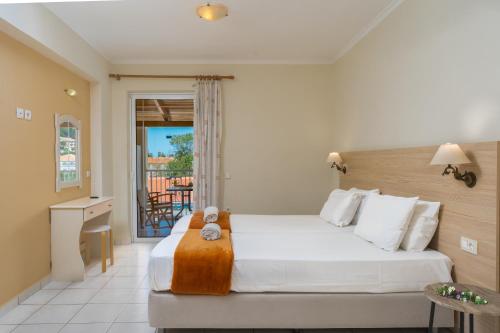 a bedroom with a large bed and a balcony at Manousis ApartHotel in Tsilivi