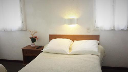 a bedroom with a bed with white pillows and a lamp at Hôtel Duchesse Anne in Lourdes
