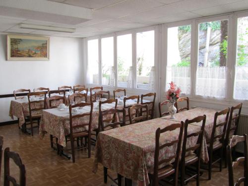 un comedor con mesas, sillas y ventanas en Hôtel Duchesse Anne, en Lourdes