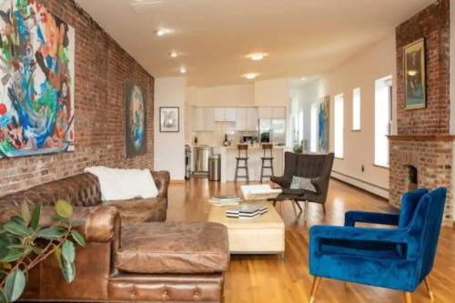 Unique 1BR Greenwich Penthouse Escape! في نيويورك: غرفة معيشة مع أريكة وجدار من الطوب