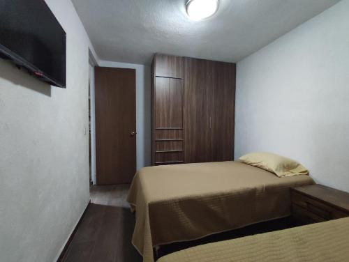 a bedroom with a bed and a closet and a television at Departamento cerca de zoológico y estadio Jalisco in Guadalajara