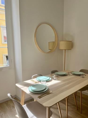 - une table à manger avec des assiettes et un miroir dans l'établissement Charmant 3 pièces à Nice, à Nice