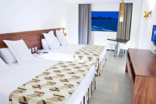 a hotel room with two beds and a desk at Ritz Suites Grand Hotel Boutique in Maceió