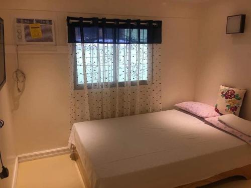 a small bedroom with a bed with a window at RJ Travellers Inn in Catbalogan