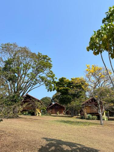 a group of buildings with trees in the background at Chalé Represa Recanto Varanda do Sol in Joanópolis