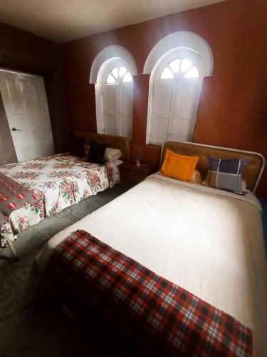 two beds in a room with two windows at HOTEL EL PANECILLO-Tanta in Quito