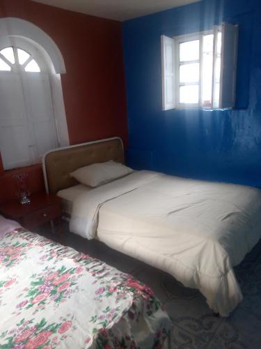 Duas camas num quarto azul com duas janelas em HOTEL EL PANECILLO-Tanta em Quito