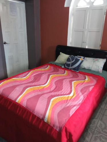 a bed with a colorful blanket on top of it at HOTEL EL PANECILLO-Tanta in Quito