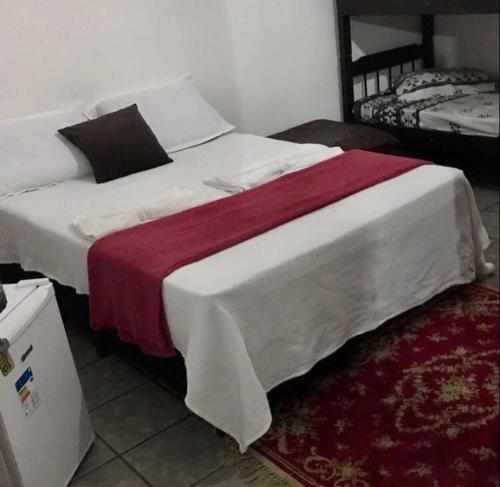 1 dormitorio con 1 cama blanca grande con manta roja en Beijaflor Pousada, en Corumbá