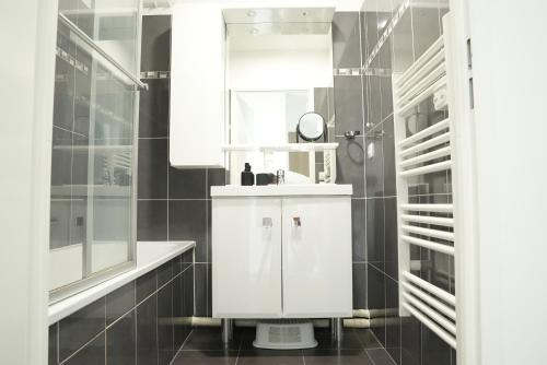 een witte badkamer met een wastafel en een spiegel bij Cosy & Charmant Appartement proche Disney in Ferrières-en-Brie