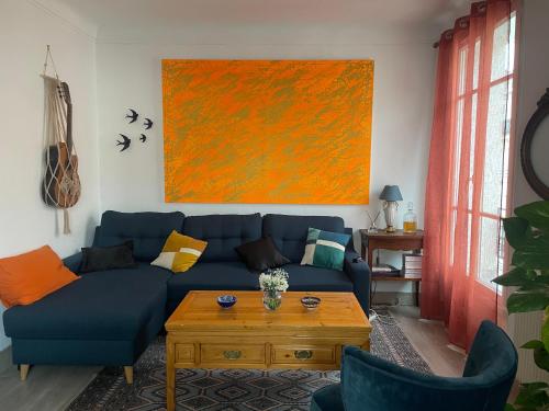 un salon avec un canapé bleu et un tableau orange dans l'établissement Appartment charming Tour Eiffel, à Paris