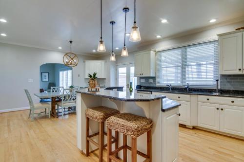 a kitchen with white cabinets and a large island with bar stools at Waterfront Cambridge Gem with Hot Tub, Pool and Dock! in Woolford