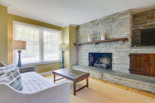 a living room with a stone fireplace and a tv at Waterfront Cambridge Gem with Hot Tub, Pool and Dock! in Woolford