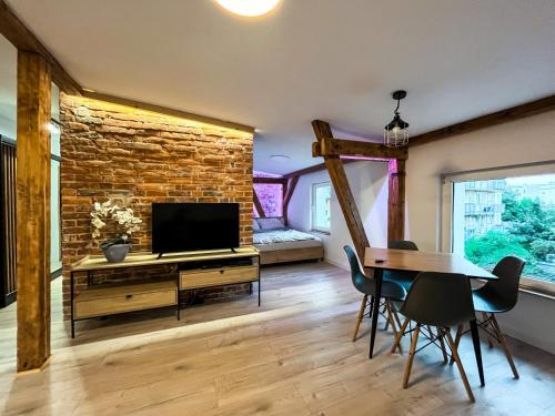 sala de estar con TV, mesa y sillas en Brick and Wood Apartment en Bydgoszcz