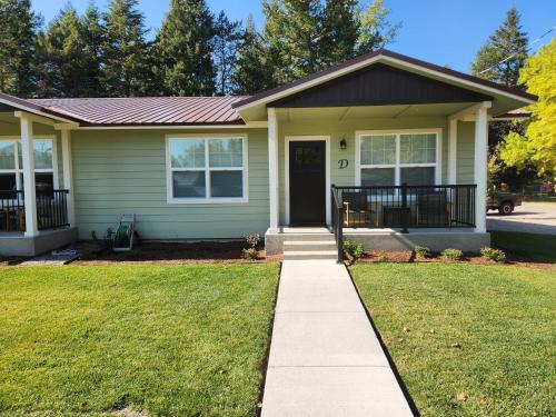 a green house with a sidewalk leading to the front door at Beargrass Lodging & RV Resort in Hungry Horse