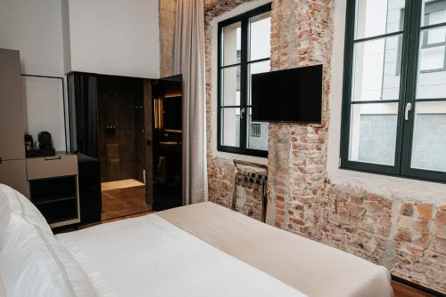 um quarto com uma cama e uma televisão numa parede de tijolos em Hotel Luruna Palacio Larrinaga em Mundaka
