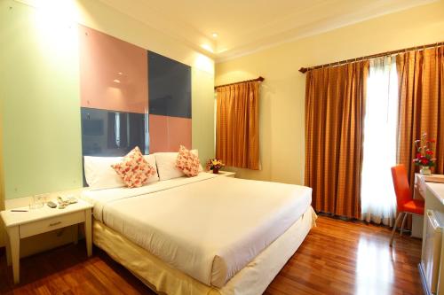 a bedroom with a large white bed and a desk at Calypzo Bangkok in Bangkok