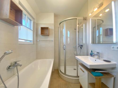 a bathroom with a tub and a sink and a shower at Lohme - Doppelhaushälfte Svantevit 2 in Ranzow in Ranzow