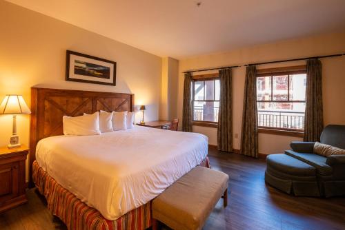 a hotel room with a large bed and a chair at The Lodge at Mountaineer Square in Mount Crested Butte