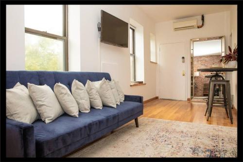 Prime Studio Greenwich Village! في نيويورك: أريكة زرقاء مع وسائد بيضاء في غرفة المعيشة