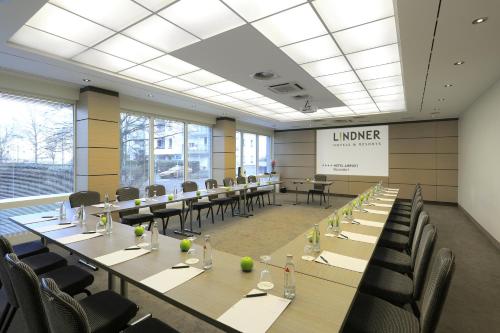 a large room with tables and chairs and a screen at Lindner Hotel Dusseldorf Airport, part of JdV by Hyatt in Düsseldorf