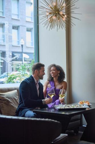 a man and woman sitting at a table with wine glasses at The Dagny Boston in Boston