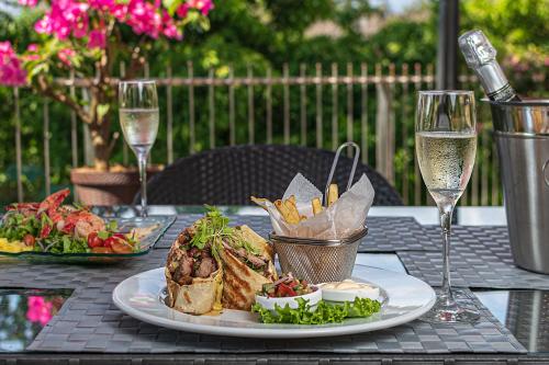 a table with a plate of food and glasses of wine at Shana by the Beach Manuel Antonio in Manuel Antonio