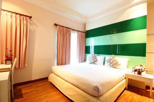 a bedroom with a large bed with a green accent wall at Calypzo Bangkok in Bangkok