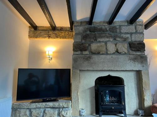 a living room with a stone fireplace with a flat screen tv at Four Double Bedroom Home - Free parking and Wi-Fi in Horsforth