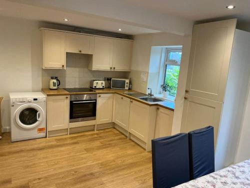 a kitchen with white cabinets and a washer and dryer at Four Double Bedroom Home - Free parking and Wi-Fi in Horsforth