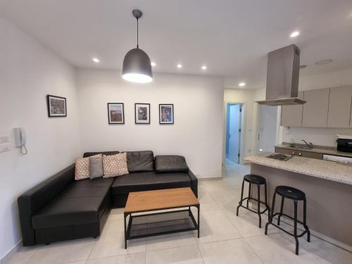 a living room with a black couch and a kitchen at No7 Boutique Apartments in Amman