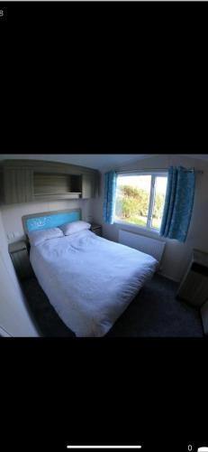 sypialnia z białym łóżkiem i oknem w obiekcie 87 kyntyre view Craig tara w mieście Ayr
