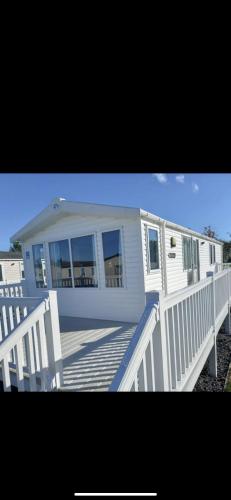 a white house with a porch and a white railing at 87 kyntyre view Craig tara in Ayr