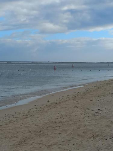 a beach with people in the water and a sail boat at Chez Diana in Flic-en-Flac