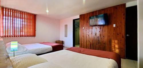 a hotel room with two beds and a tv at Hotel El Gran Chaparral in Calarcá