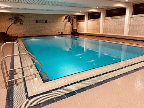 a large swimming pool with blue water in a building at GenoHotel Forsbach in Rösrath