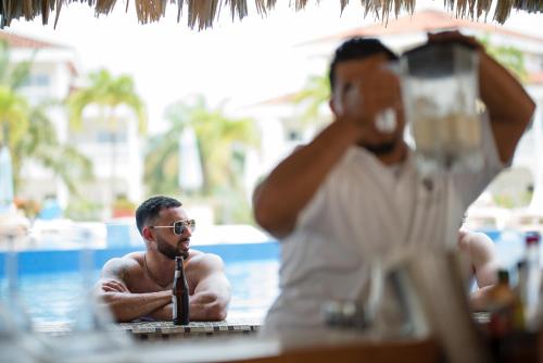a man in a swimming pool with a microphone at Placencia Resort in Maya Beach