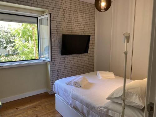 um quarto com uma cama, uma janela e uma televisão em T2 Alvalade em Lisboa para 3 Pessoas em Lisboa
