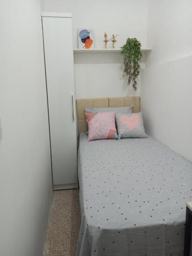 een kleine slaapkamer met een bed met roze kussens bij Temporada Paulistana exclusivo para Mulheres in Sao Paulo